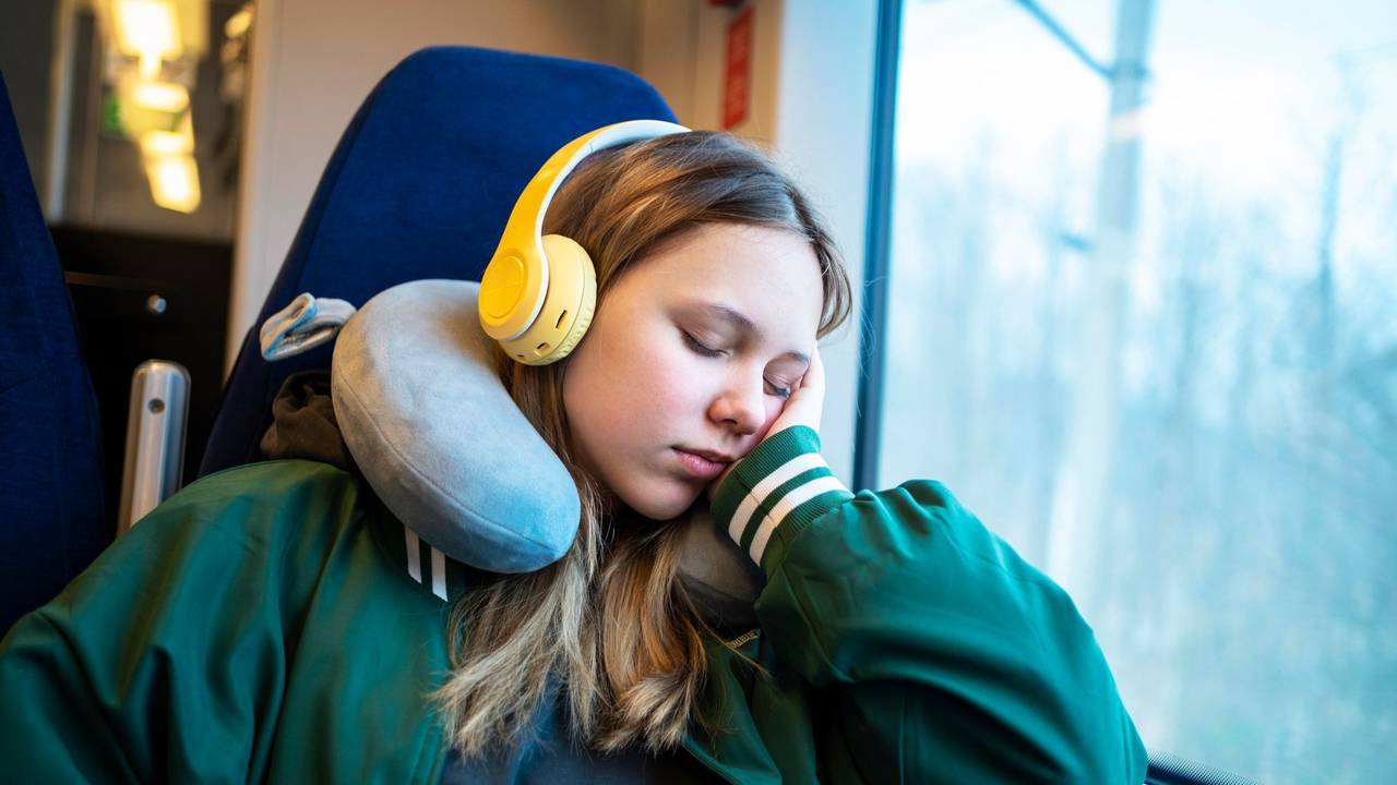 Mädchen schläft mit einem Nackenkissen im Zug