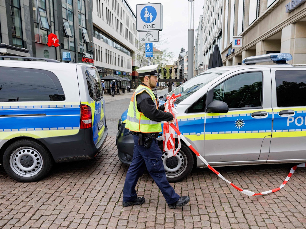 Ein Polizist entfernt am 5. Mai 2026 die Absperrung am Eingang zur Fußgängerzone der Grimmaischen Straße in Leipzig, unweit der Stelle, an der ein Auto in eine Menschenmenge gerast war und dabei zwei Menschen getötet und mehrere verletzt hatte.