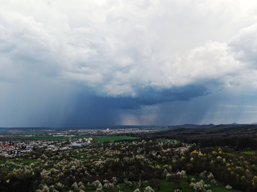 Regenwolken über einer Stadt und blühender Landschaft