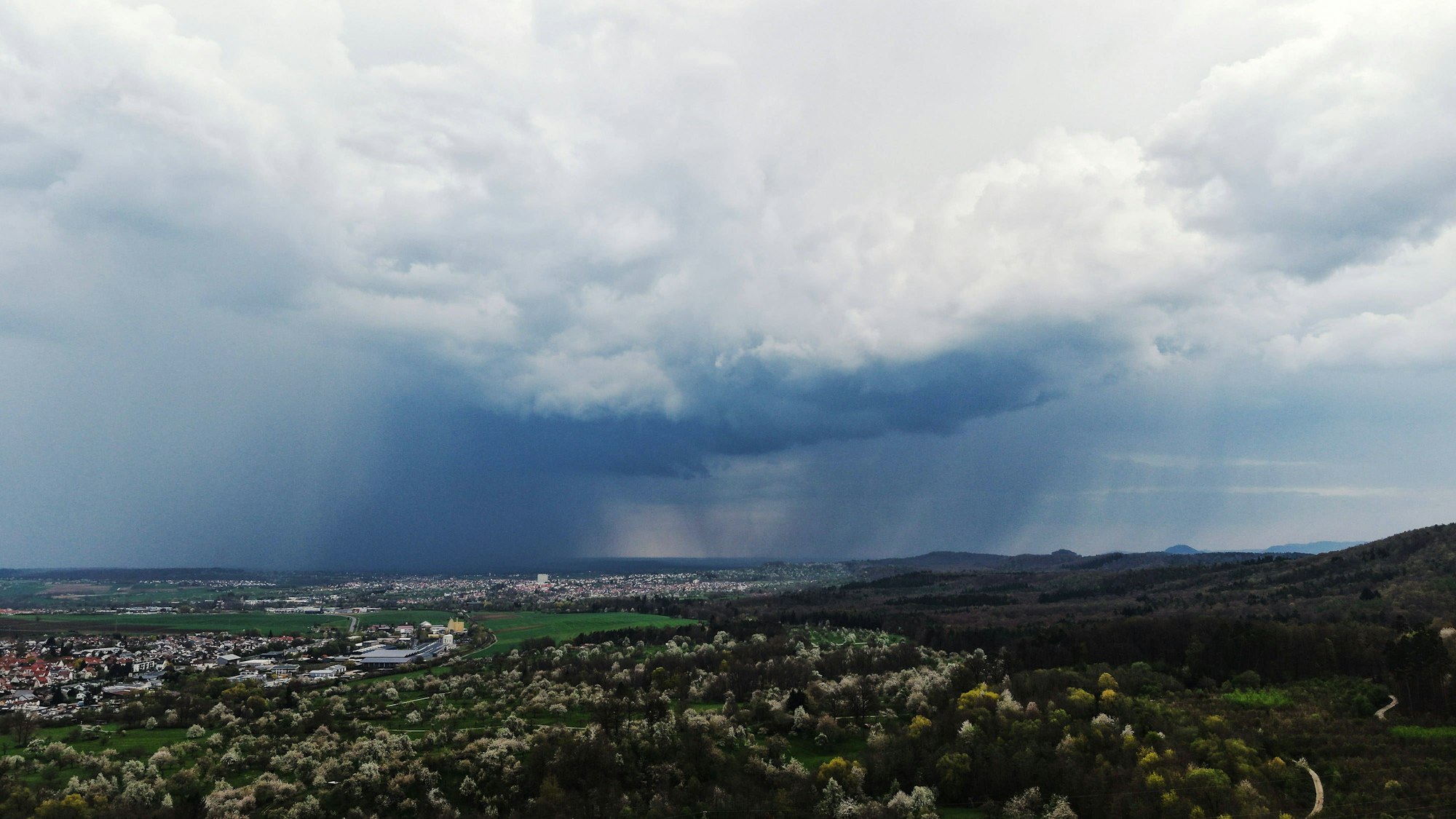 Regenwolken über einer Stadt und blühender Landschaft