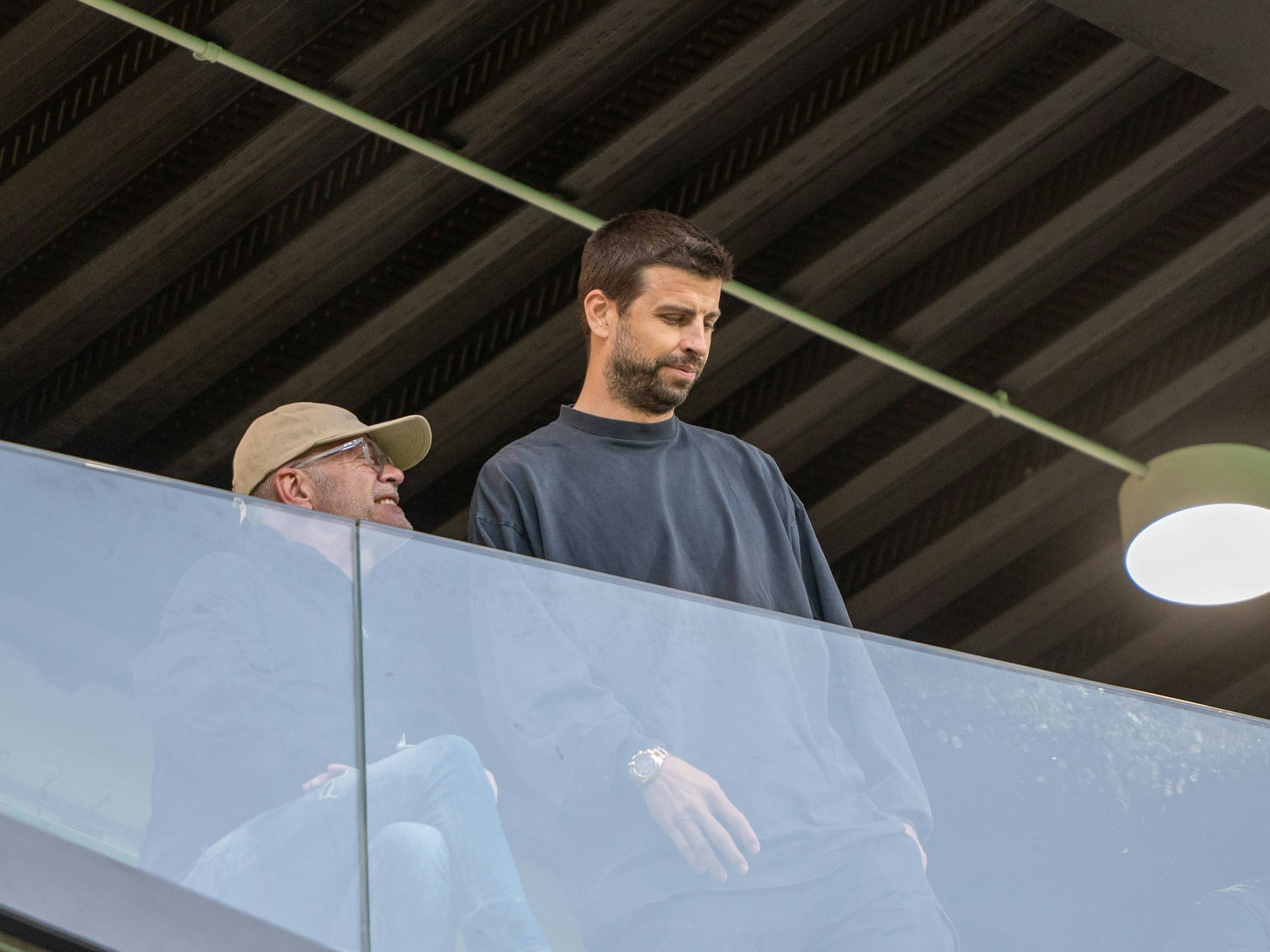 Gerard Piqué auf der Tribüne hinter einer Glasballustrade.