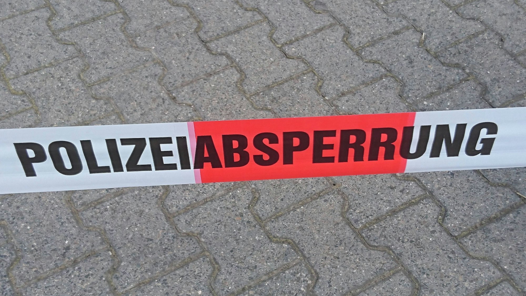 Symbolische Polizeiabsperrung auf Pflastersteinen