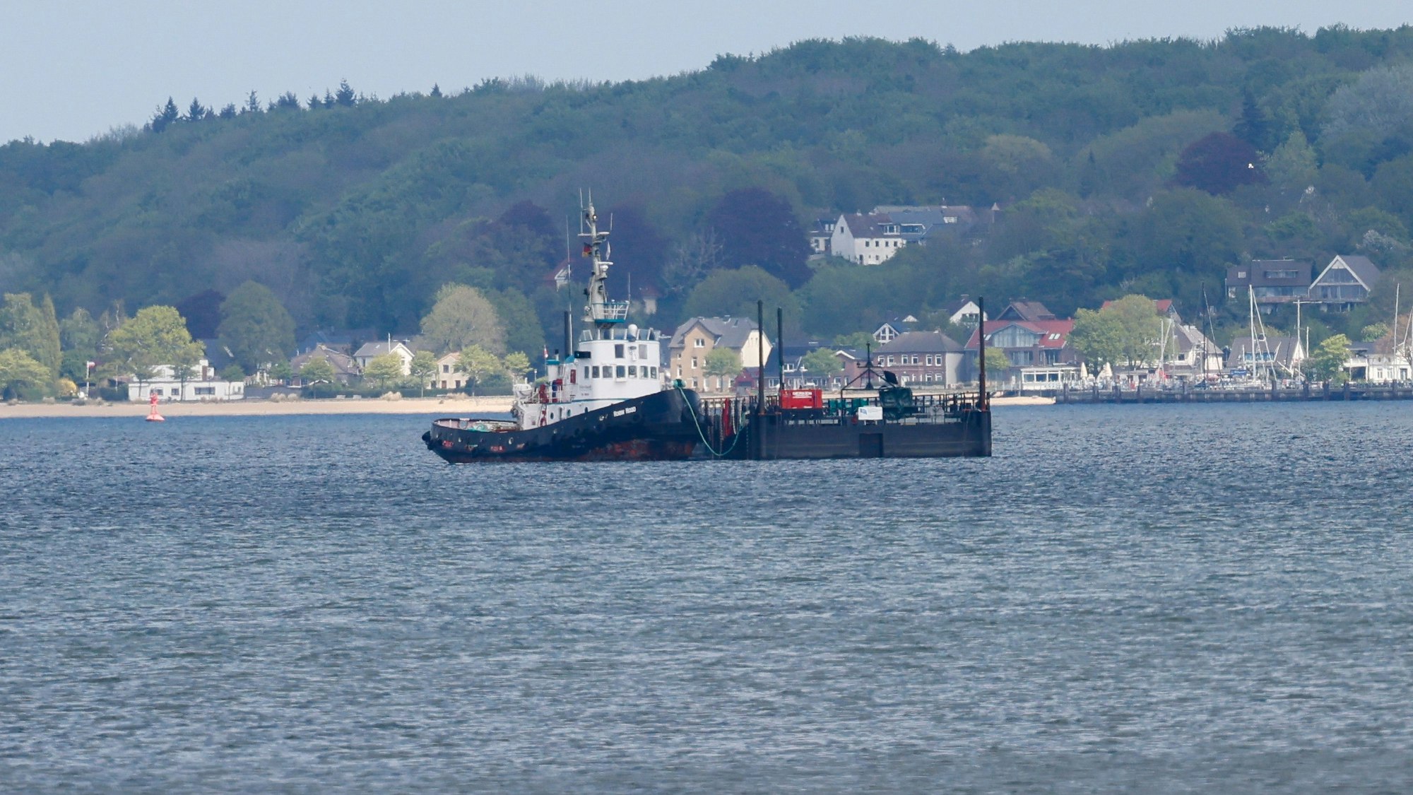 Der Schlepper „Robin Hood“ und die Barge liegen auf der Kieler Förde. Das Schiff aus Bremerhaven begleitete den Transport des gestrandeten Buckelwals auf dem Weg zurück in die Nordsee.