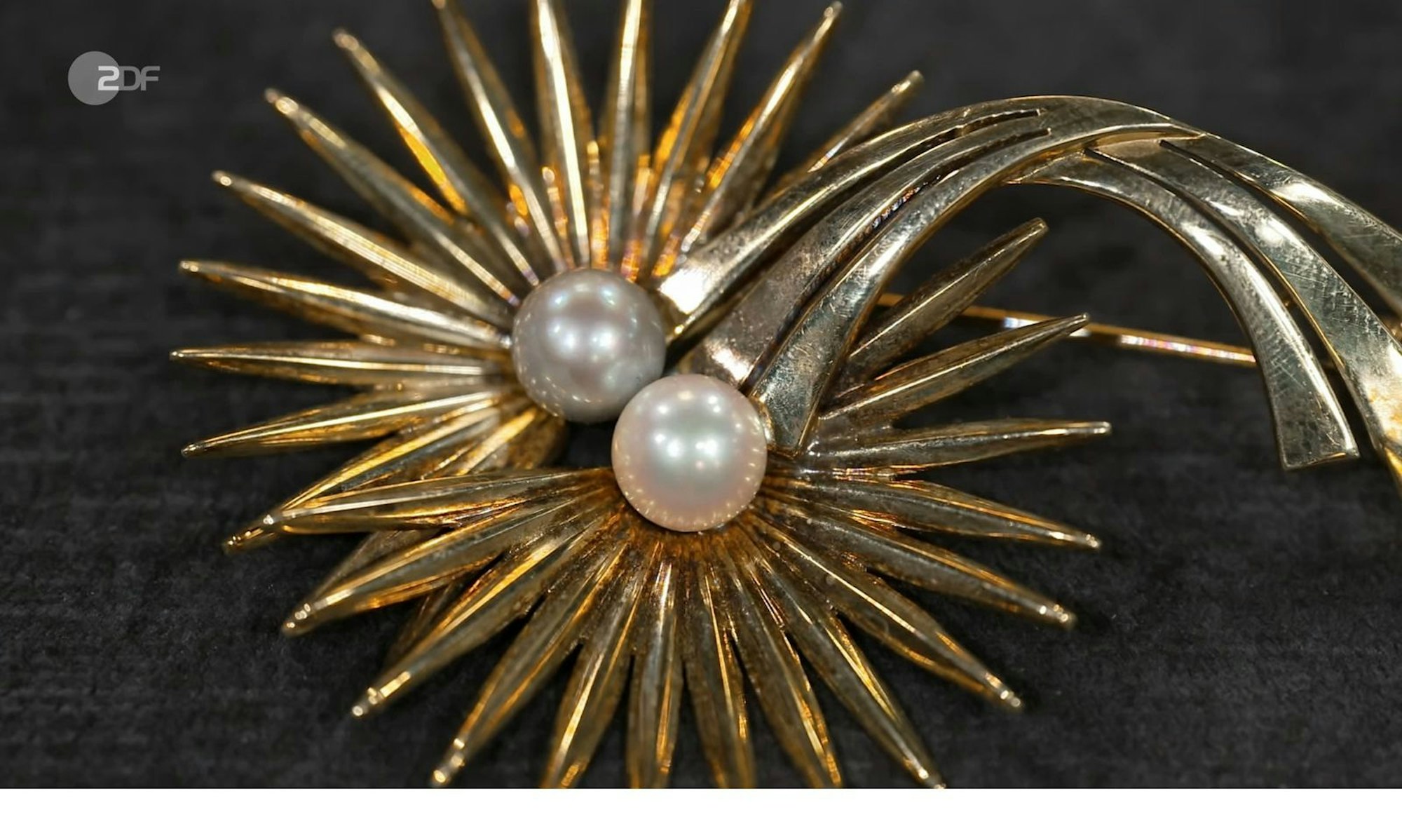 Auch das nächste Schmuckstück ließ das Händlerteam genauer hinschauen. Die elegante Brosche aus den 1940er-Jahren war mit zwei Perlen besetzt und brachte ordentlich Glanz mit. Nach eingehender Prüfung lag die Expertise bei 950 Euro. (Bild: ZDF)