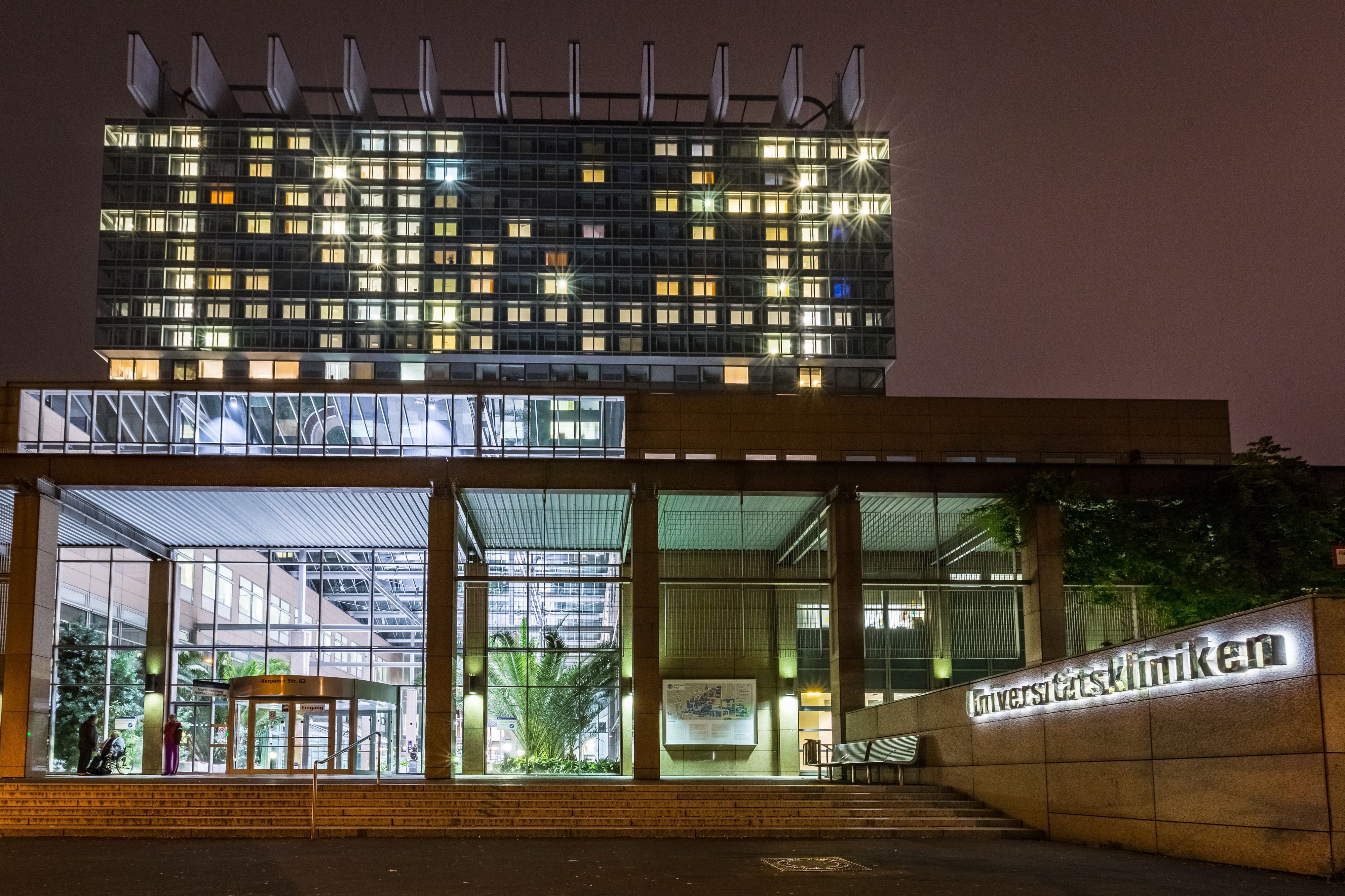 Das Hauptgebäude der Universitätskliniken Köln ist am Abend hell erleuchtet.