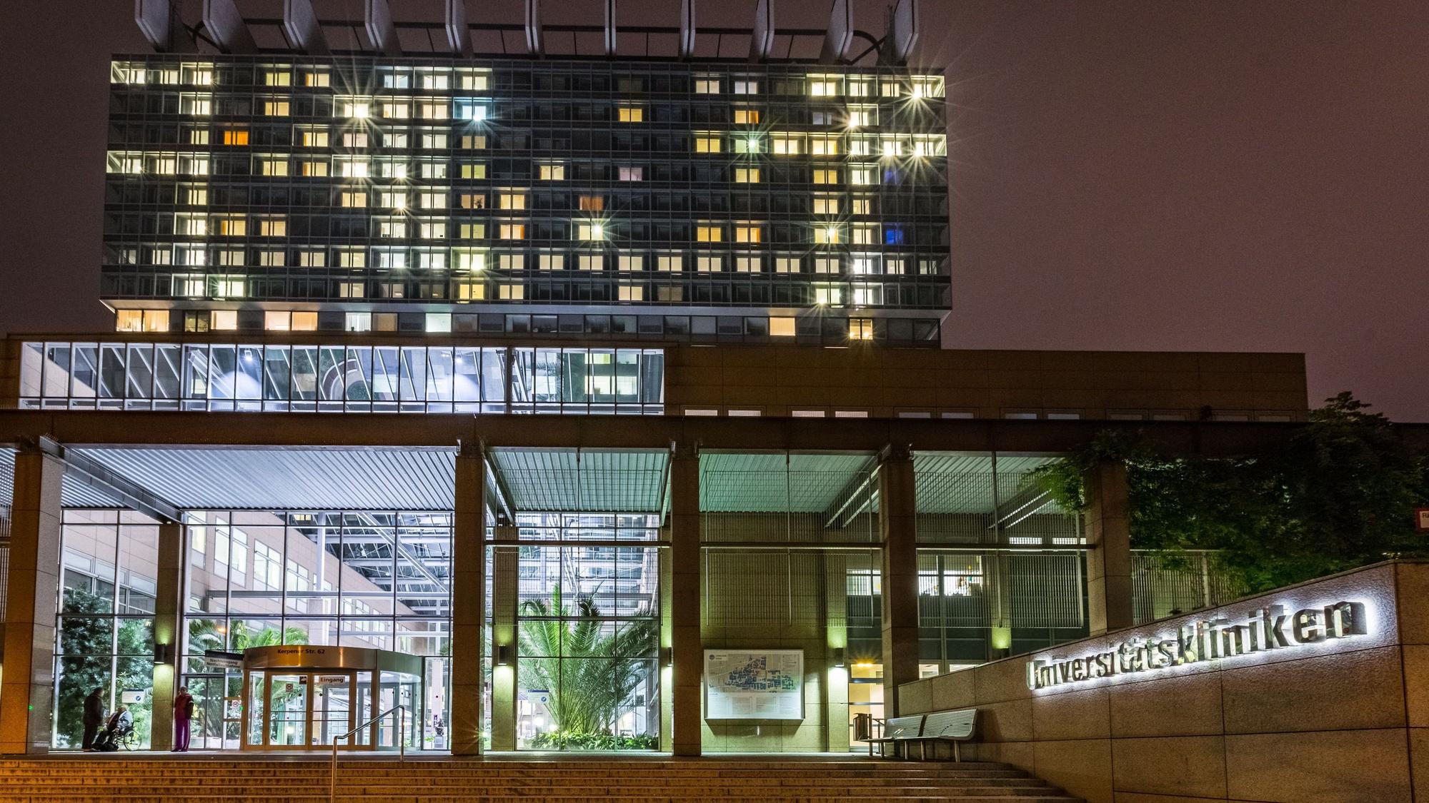 Das Hauptgebäude der Universitätskliniken Köln ist am Abend hell erleuchtet.