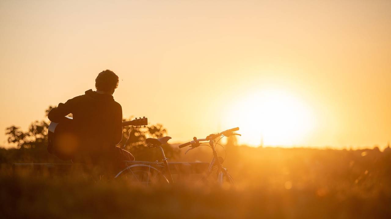 Mann spielt im Licht der aufgehenden Morgensonne Gitarre
