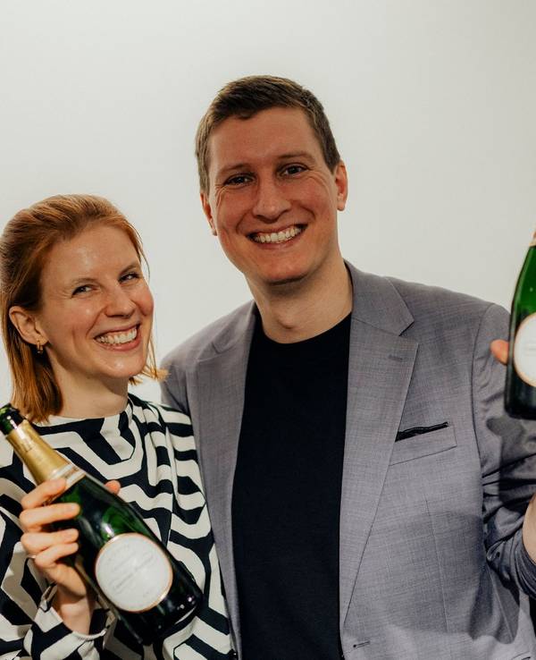 Timo und Katrin Brecht mit Sektflaschen in der Hand.