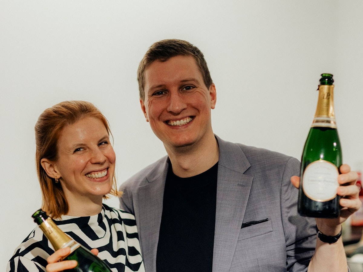Timo und Katrin Brecht mit Sektflaschen in der Hand.