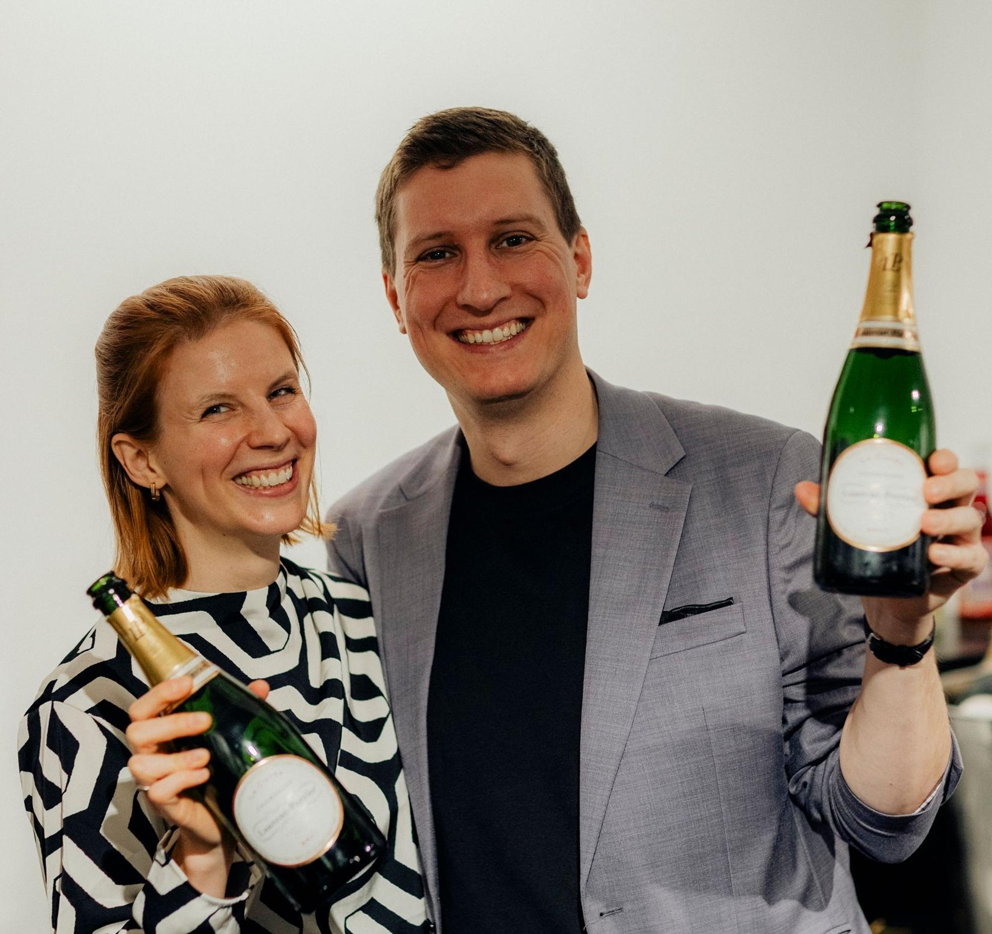 Timo und Katrin Brecht mit Sektflaschen in der Hand.