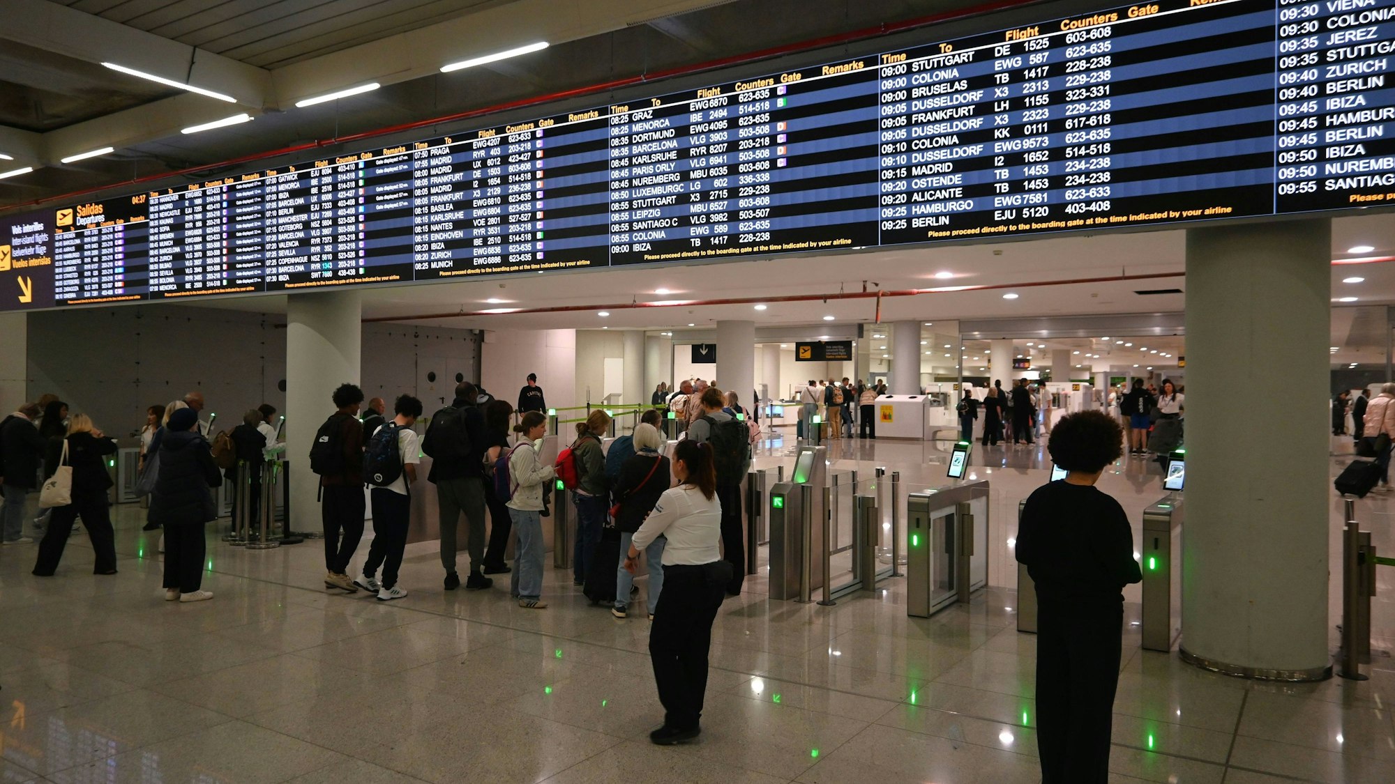 Menschen am Flughafen Palma mit Abflugtafel