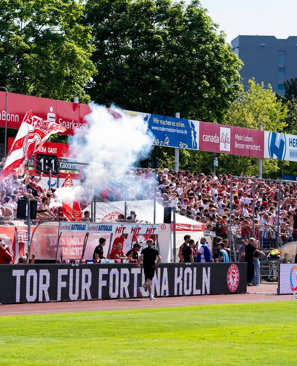 Die Fans von Fortuna Köln freuen sich auf der Tribüne und zünden Pyrotechnik.