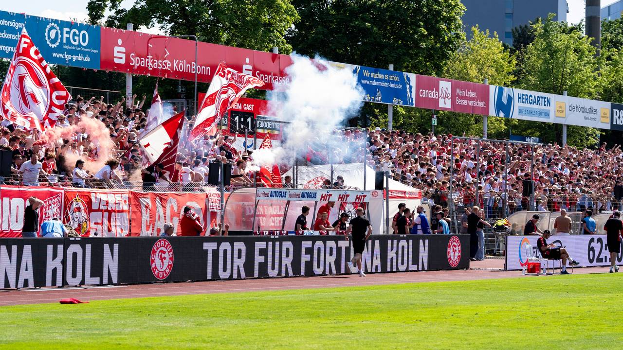 Die Fans von Fortuna Köln freuen sich auf der Tribüne und zünden Pyrotechnik.