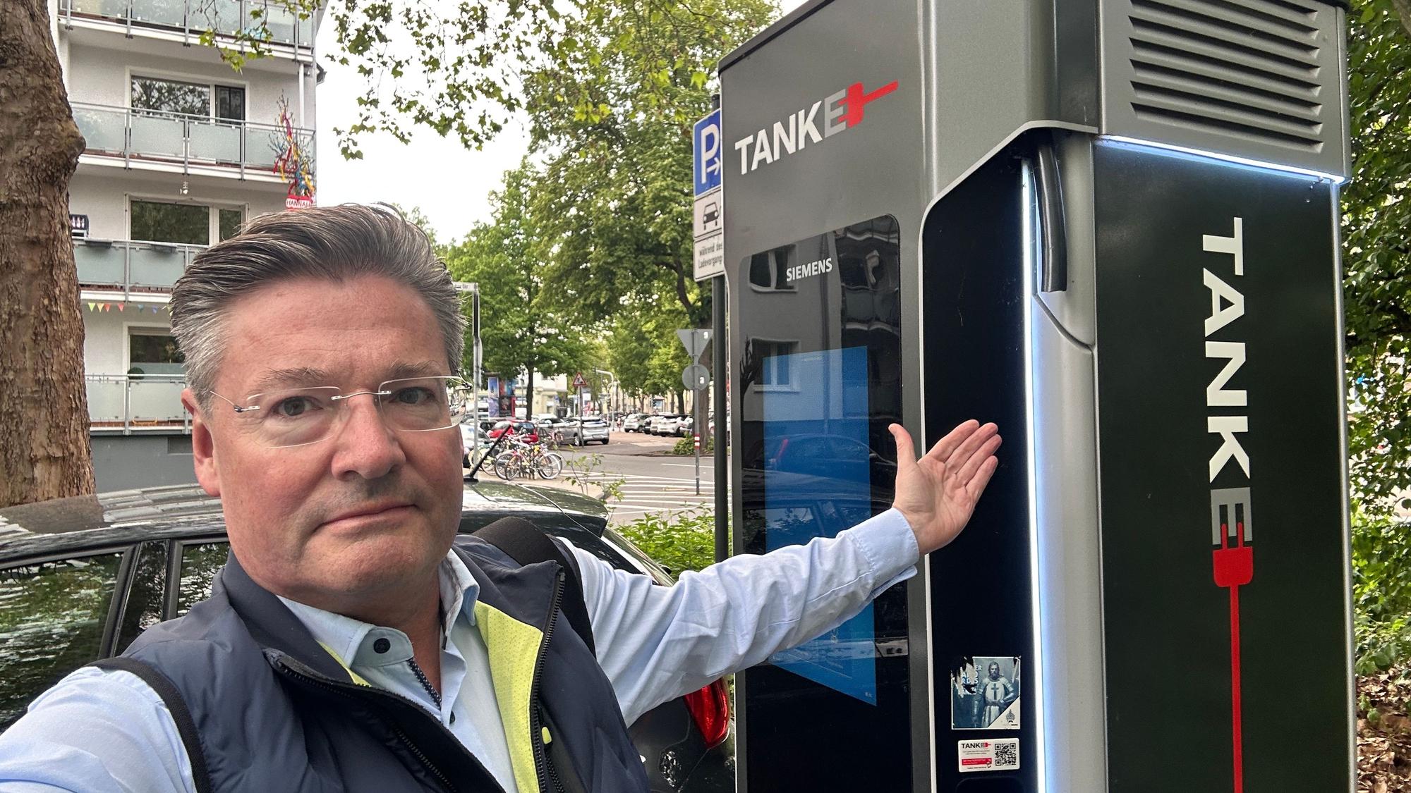 Torsten Ilg von der Kölner StadtGesellschaft (KSG) zeigt auf eine kaputte Ladestation in Köln-Zollstock.