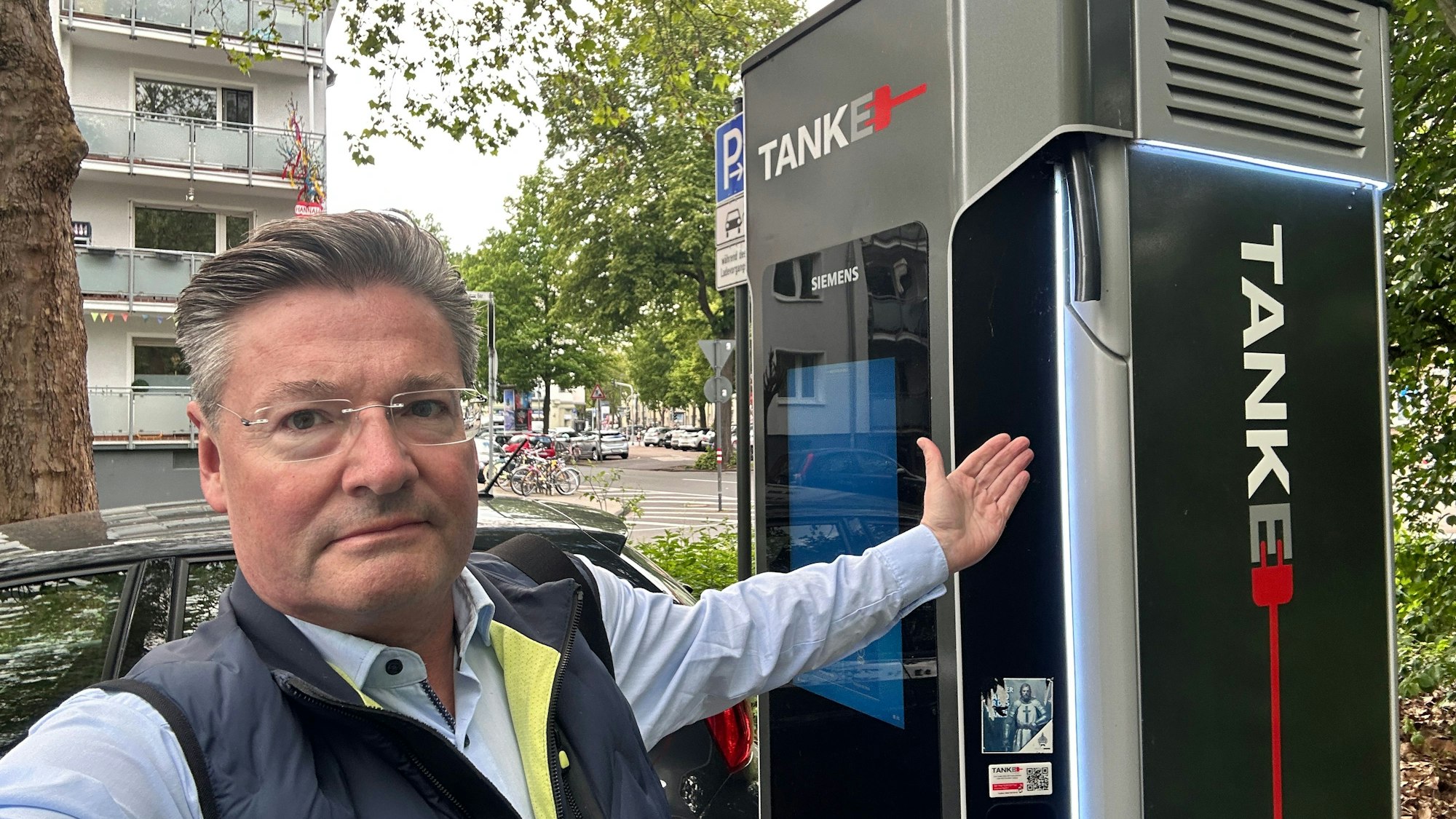 Torsten Ilg von der Kölner StadtGesellschaft (KSG) zeigt auf eine kaputte Ladestation in Köln-Zollstock.