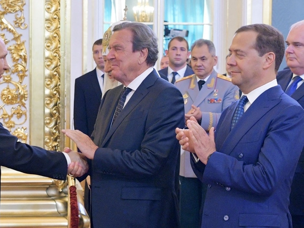 Wladimir Putin und der deutsche Ex-Bundeskanzler Gerhard Schröder schütteln im Mai 2018 Hände.