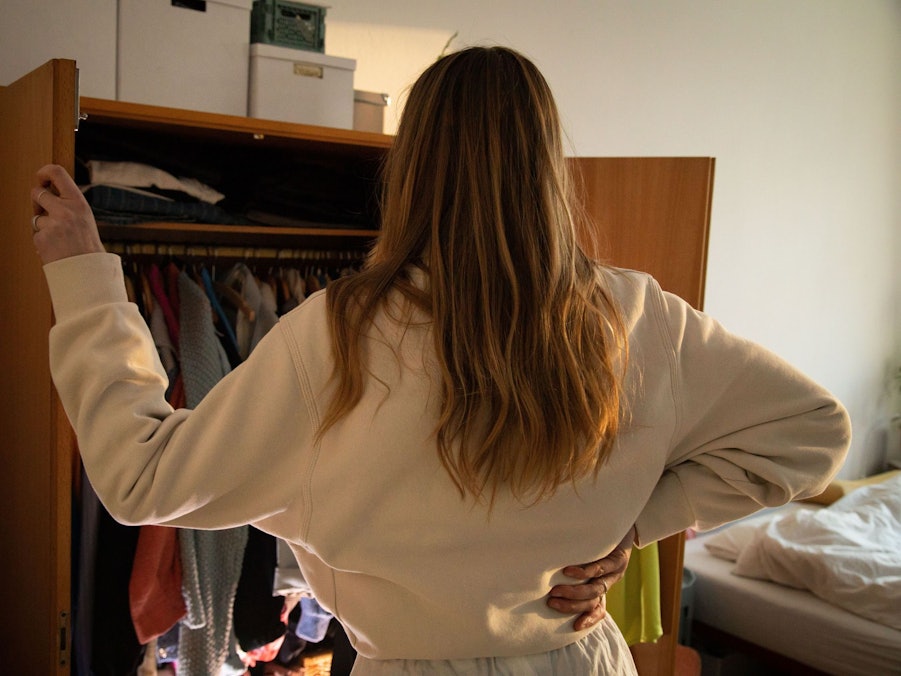 Eine Frau steht vor ihrem geöffneten Kleiderschrank