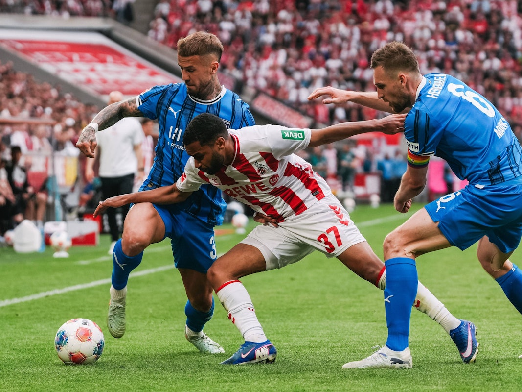 Zweikampf zwischen Linton Maina (Köln) und Niklas Dorsch sowie Patrick Mainka (Heidenheim).