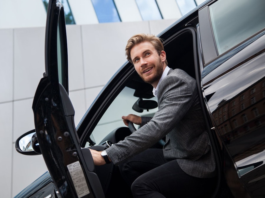 Ein Mann sitzt im Auto bei geöffneter Tür