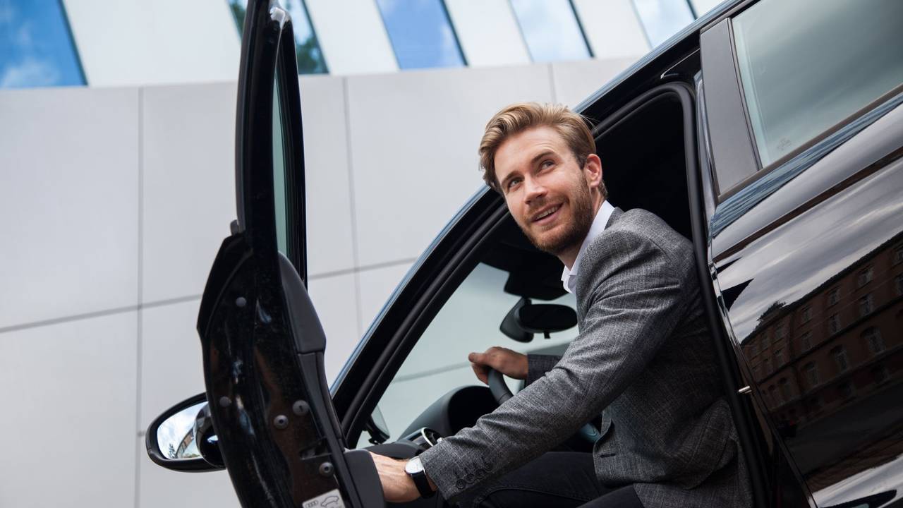 Ein Mann sitzt im Auto bei geöffneter Tür