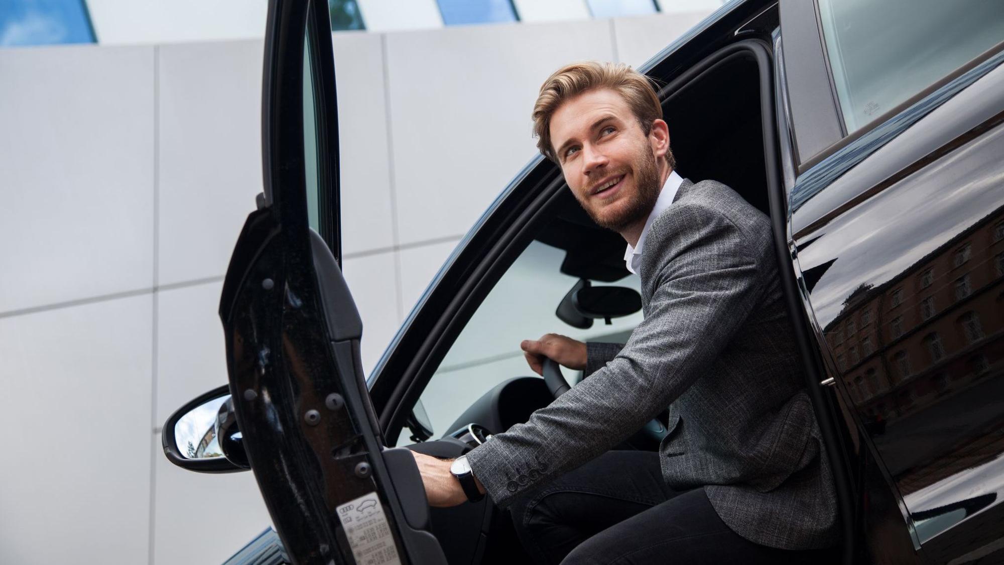 Ein Mann sitzt im Auto bei geöffneter Tür
