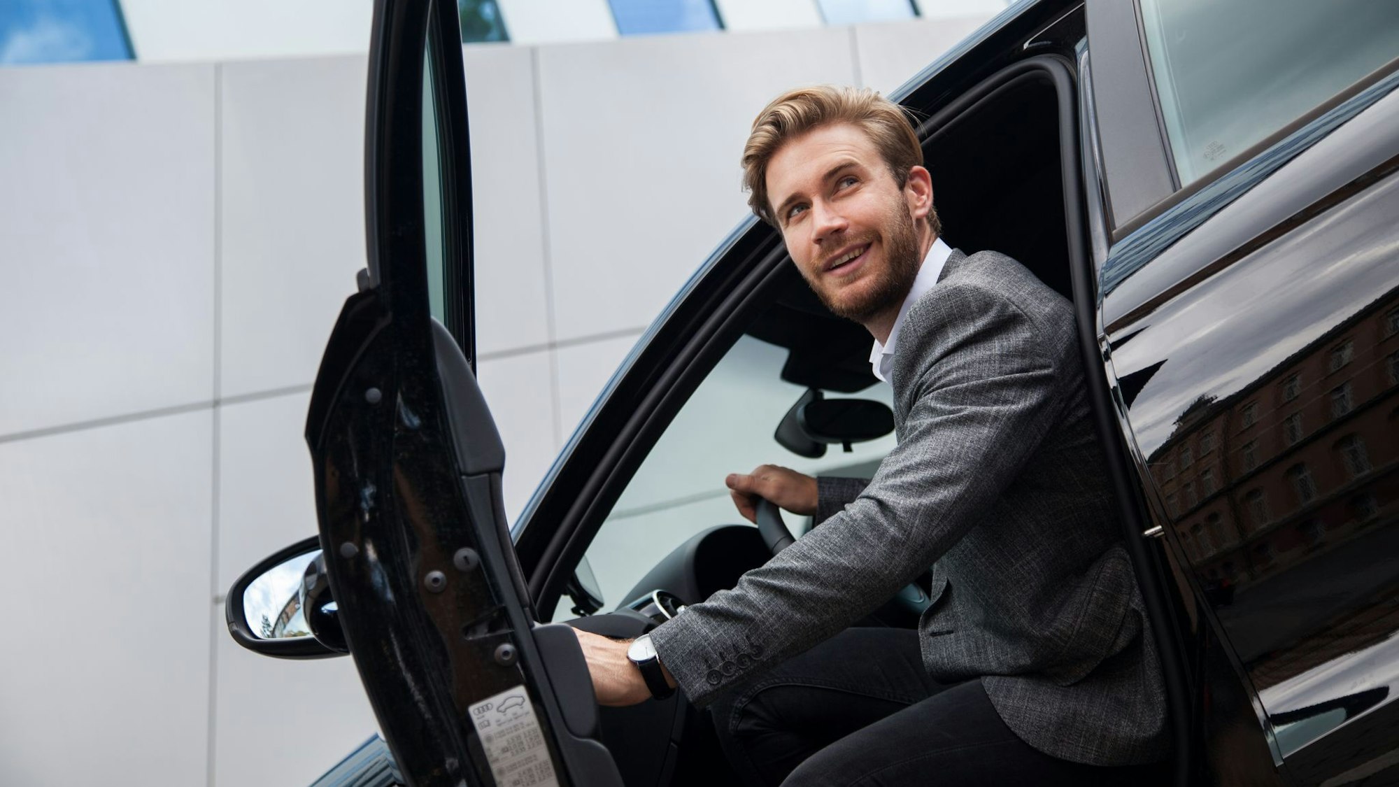 Ein Mann sitzt im Auto bei geöffneter Tür