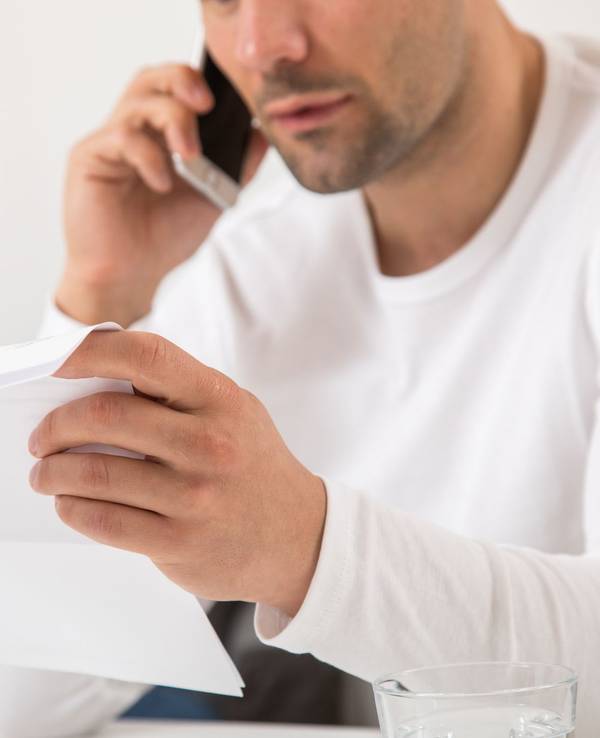 Mann telefoniert mit einem Brief in der Hand