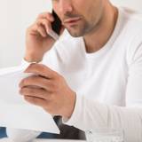 Mann telefoniert mit einem Brief in der Hand