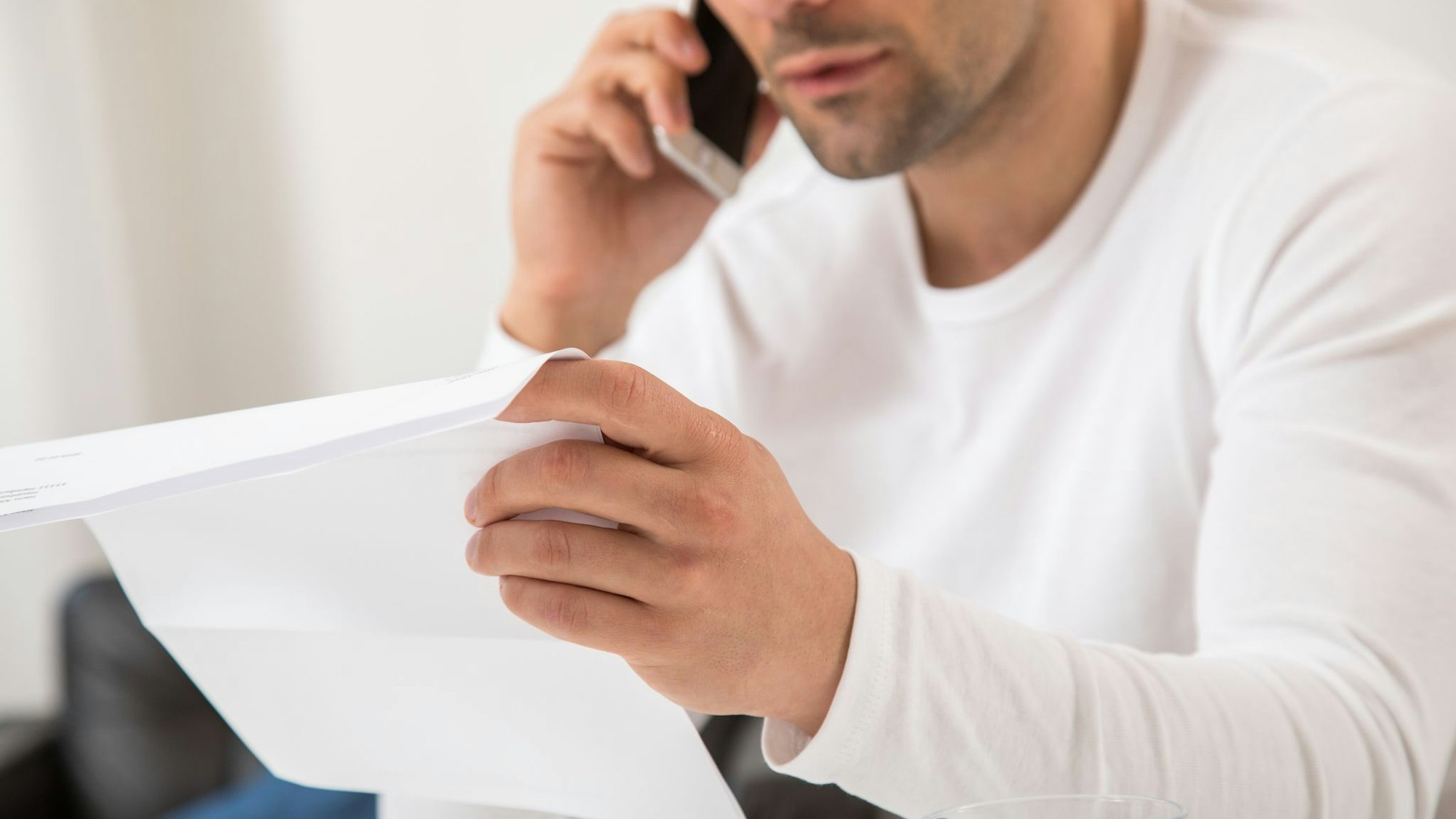 Mann telefoniert mit einem Brief in der Hand