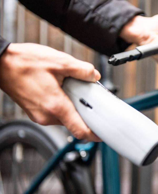 Person schließt ein Fahrrad an einem Zaun an