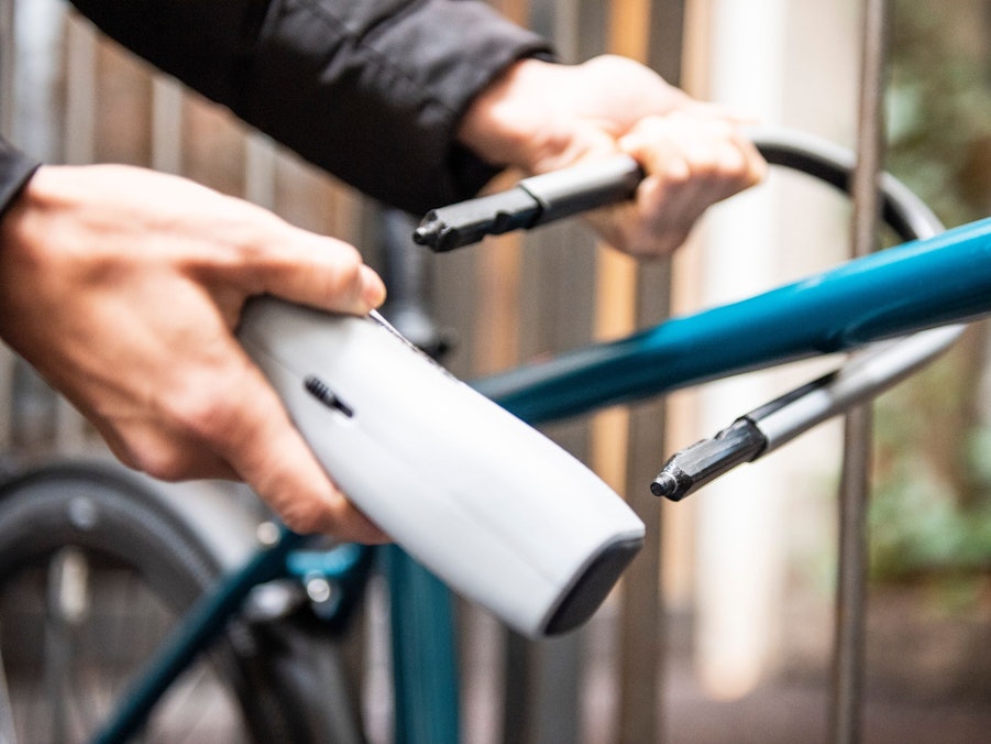 Person schließt ein Fahrrad an einem Zaun an