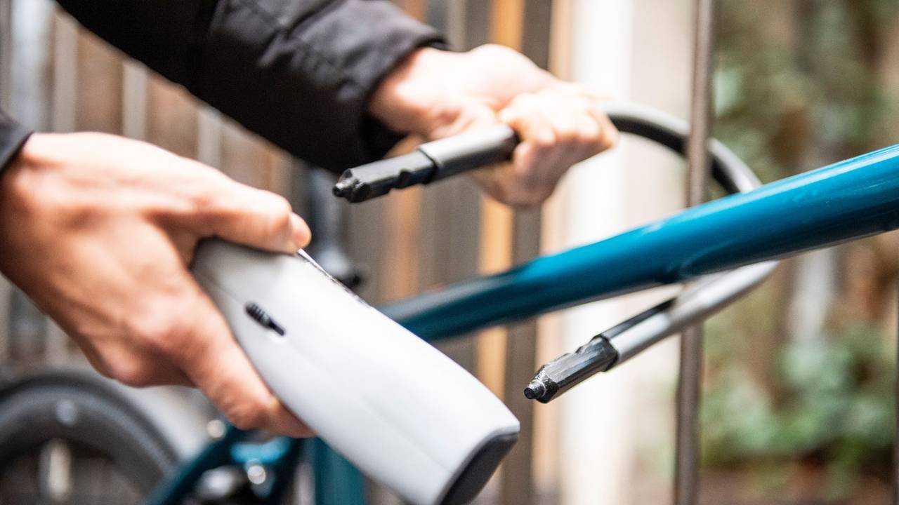 Person schließt ein Fahrrad an einem Zaun an