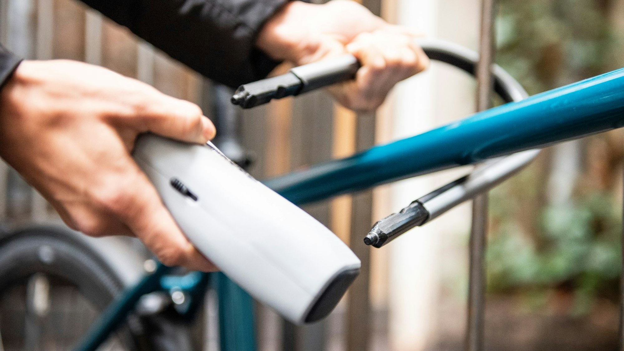 Person schließt ein Fahrrad an einem Zaun an