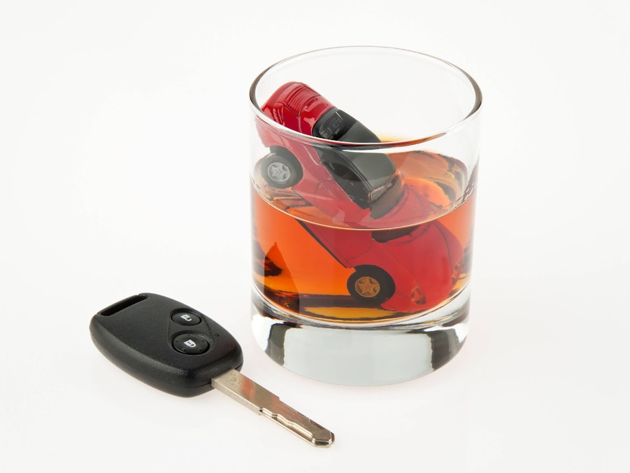 Ein Glas Alkohol mit Spielzeugauto und Autoschlüssel