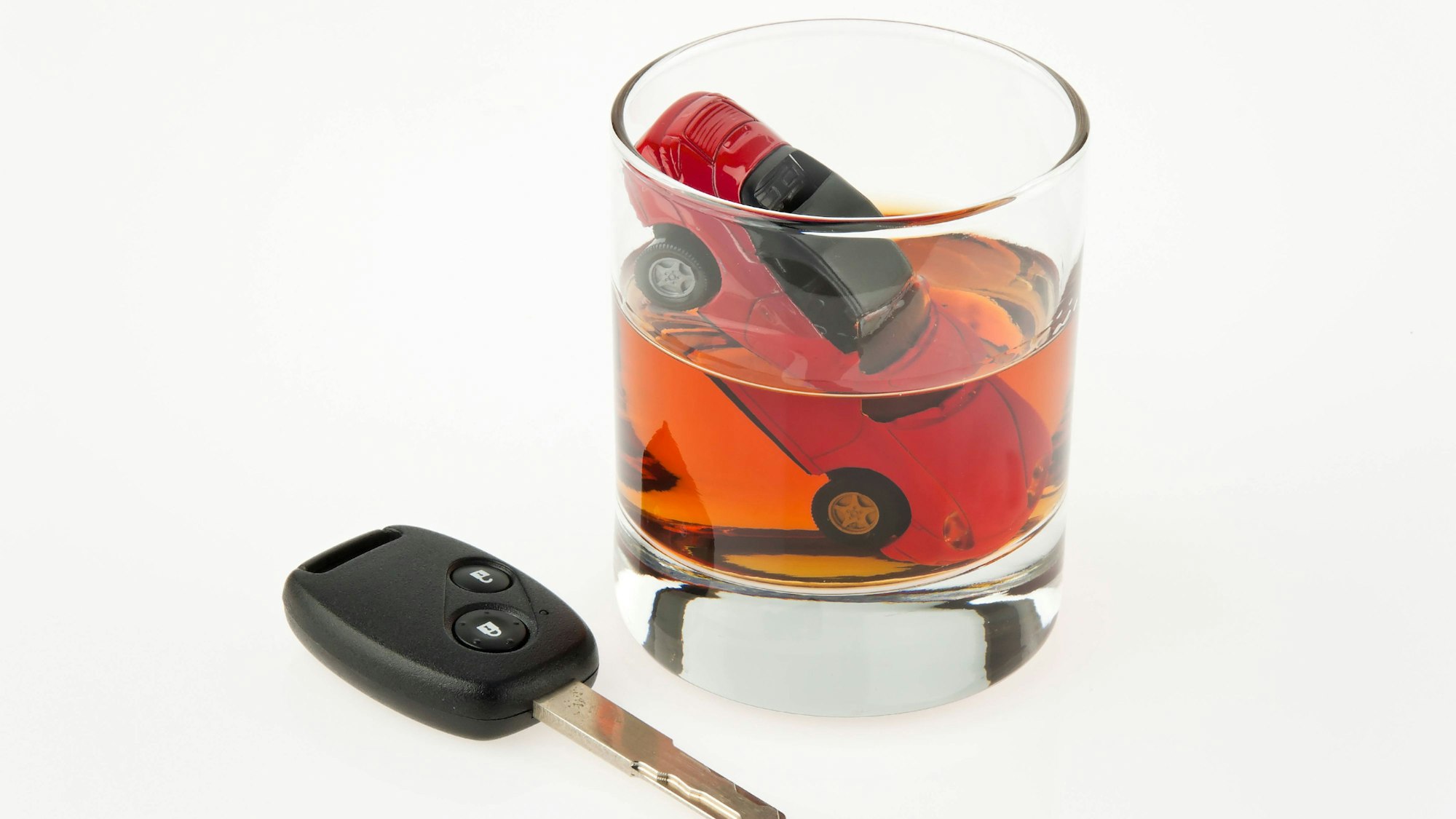 Ein Glas Alkohol mit Spielzeugauto und Autoschlüssel