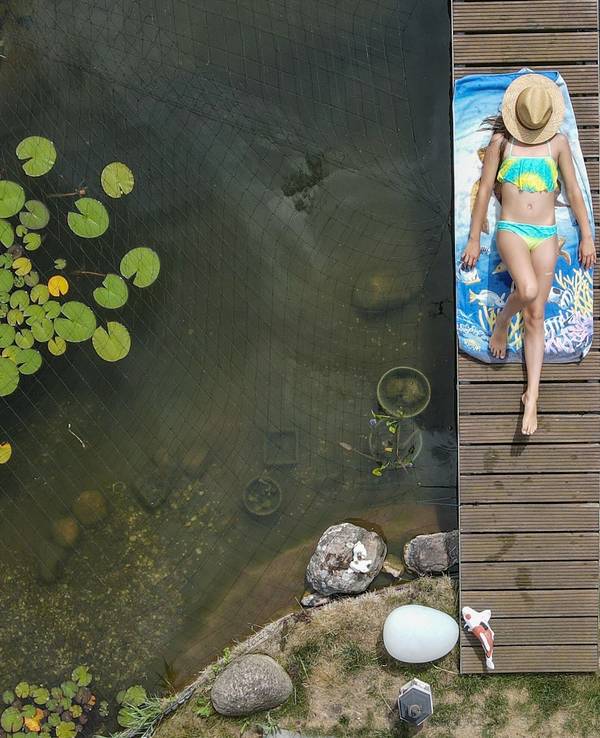 Mädchen sonnt sich auf einer Brücke über einem Gartenteich