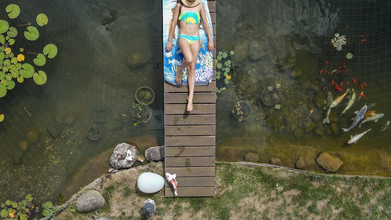 Mädchen sonnt sich auf einer Brücke über einem Gartenteich