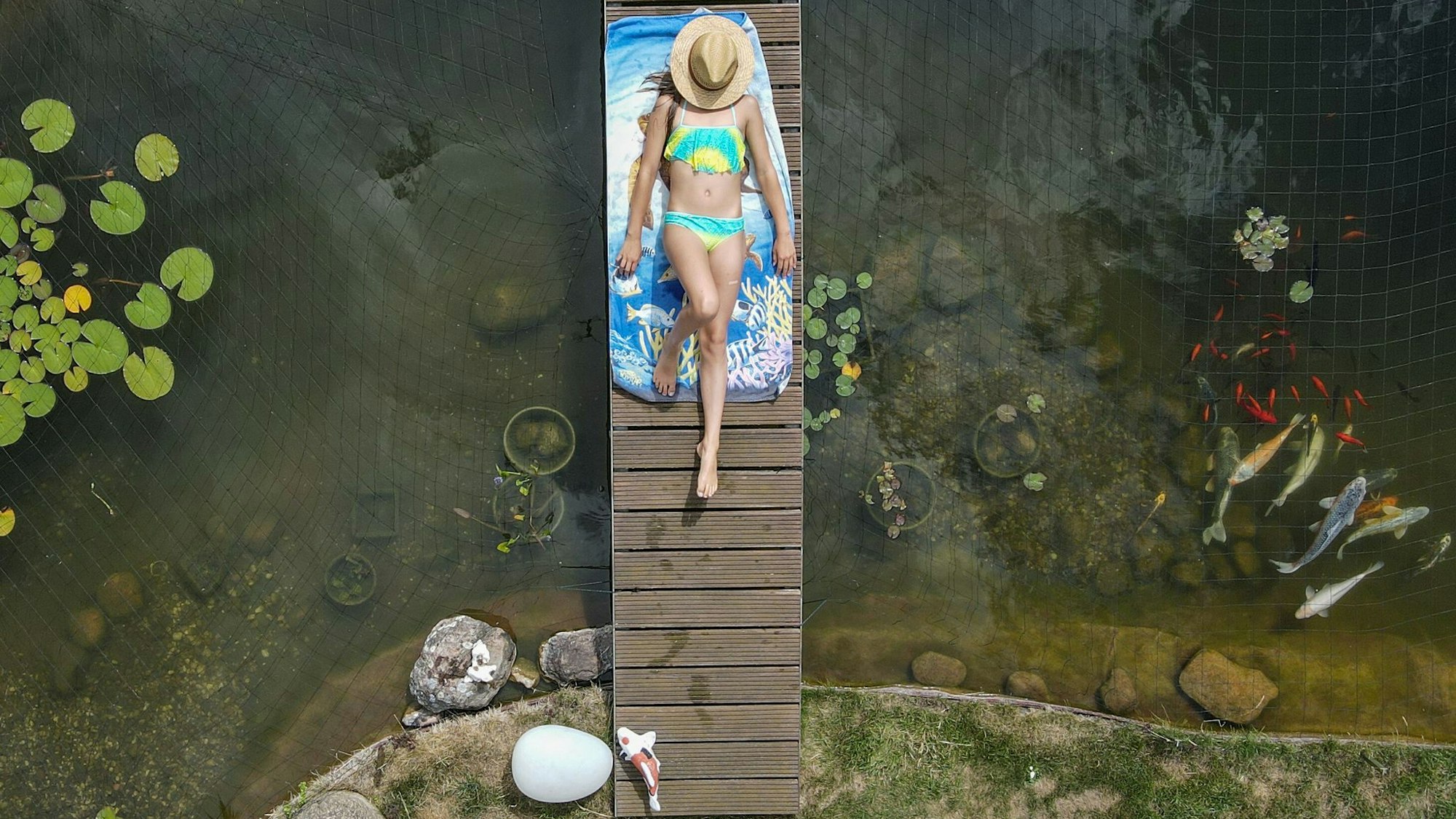 Mädchen sonnt sich auf einer Brücke über einem Gartenteich