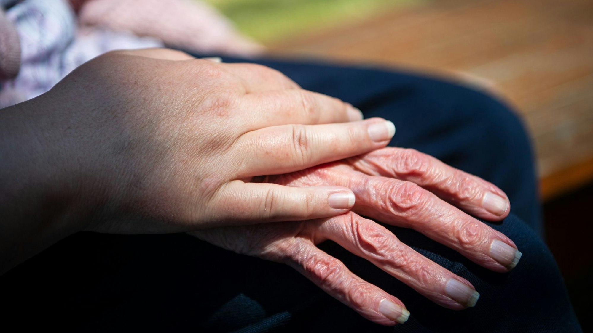 Hand einer Pflegefachkraft liegt auf Hand eienr Seniorin