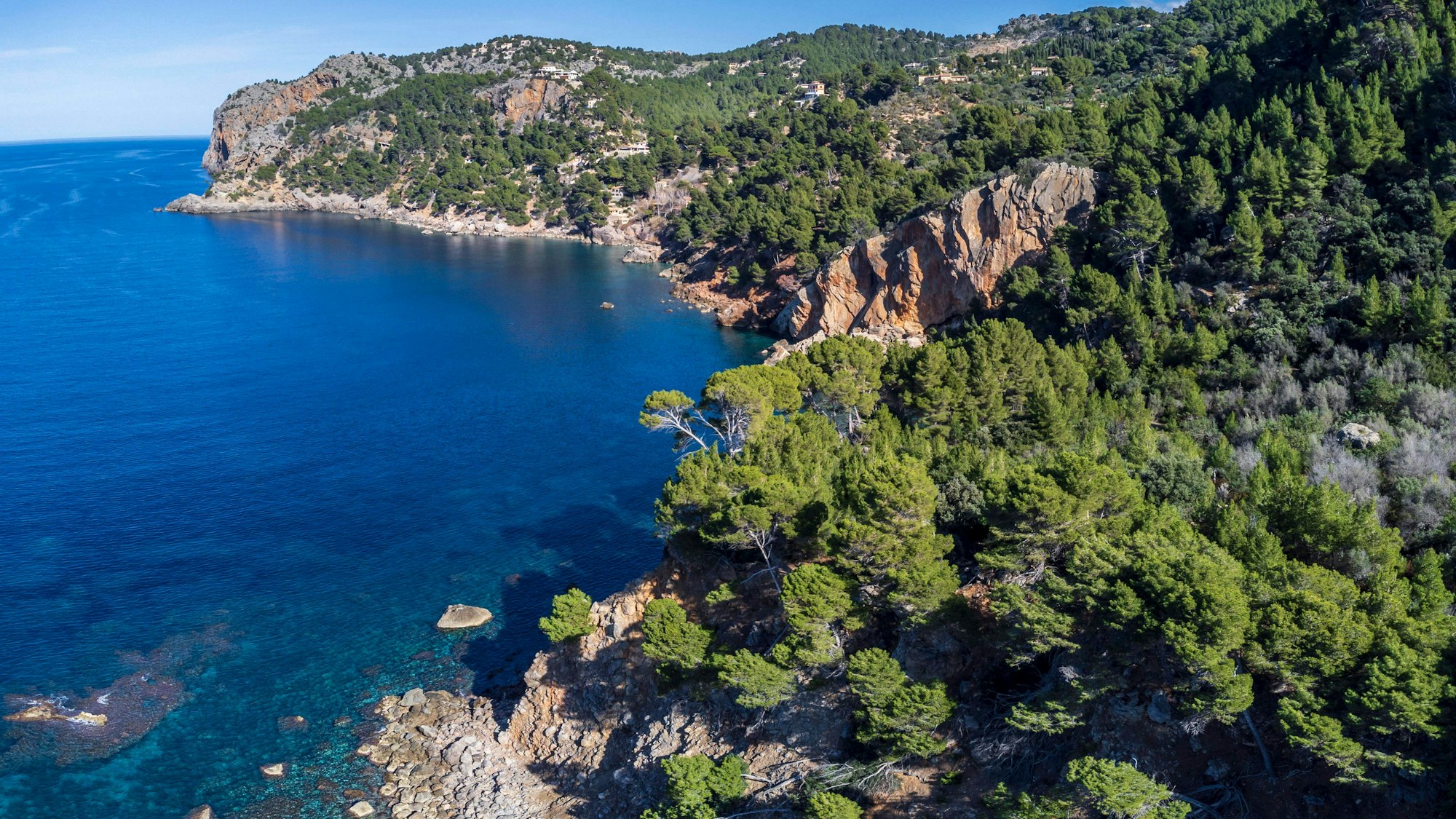 Küste, Meer, bewaldete Berge und Häuser