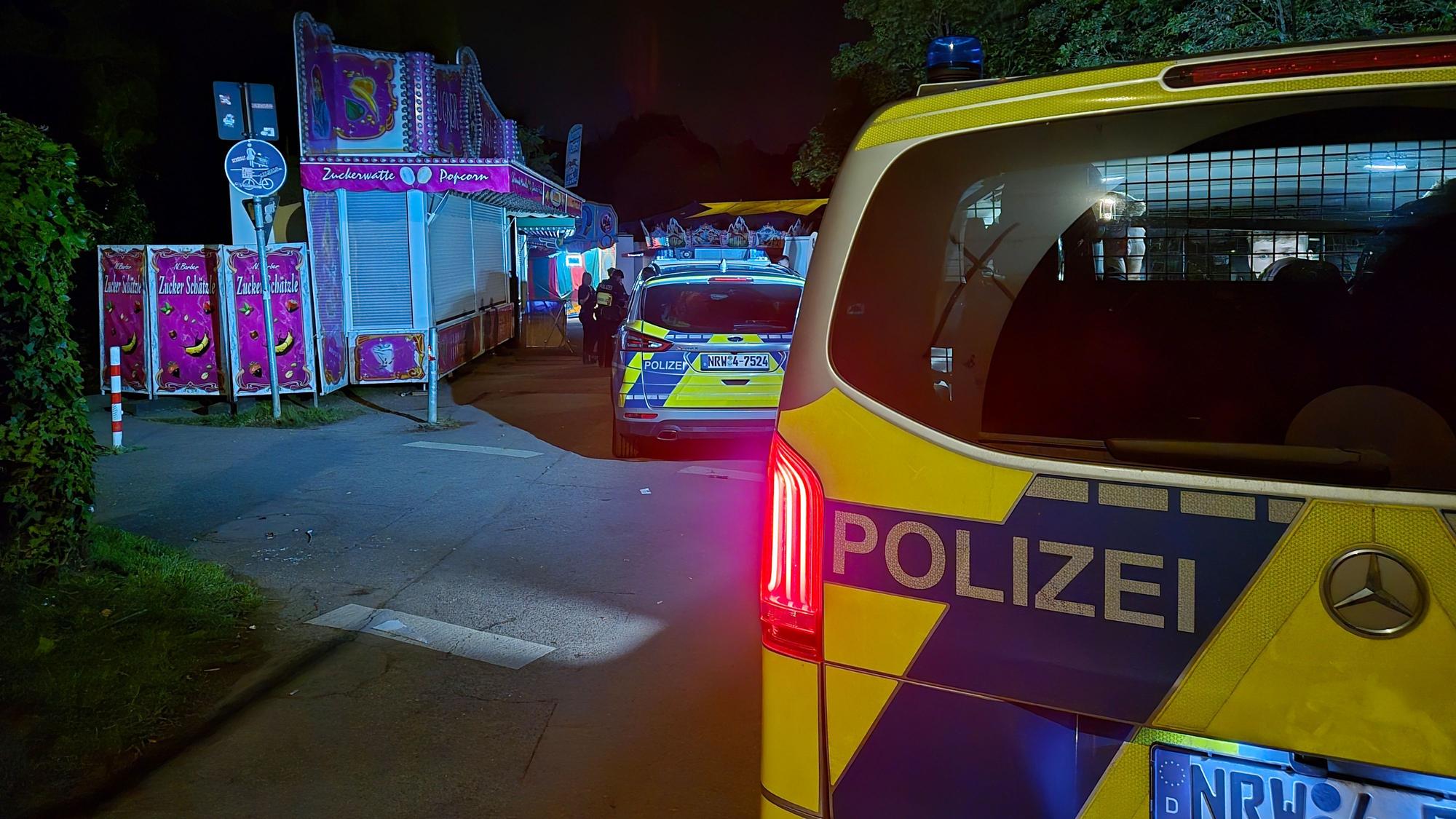 Einsatzkräfte und Streifenwagen stehen auf einem Kirmesgelände.