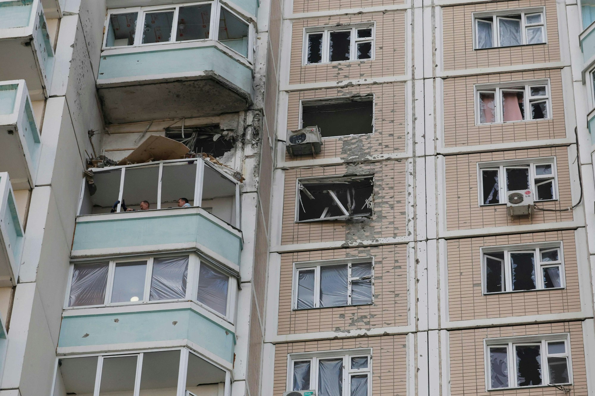 Anwohner begutachten nach einem Luftangriff in Krasnogorsk in der Region Moskau einen beschädigten Balkon in einem Wohnhaus.