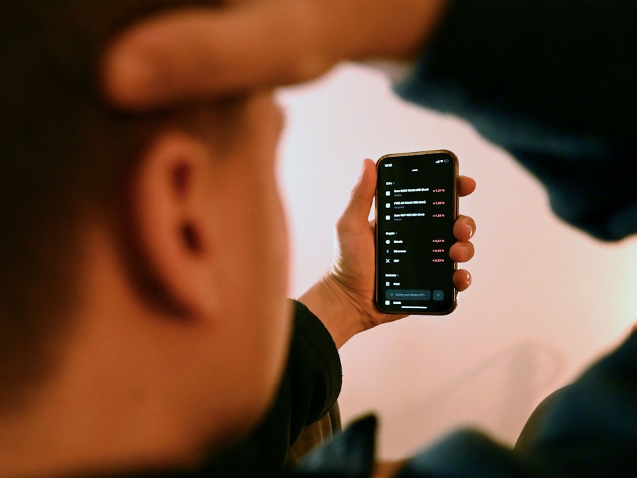 Mann schaut sich Trading-App eines Neobrokers mit Aktienkursen an