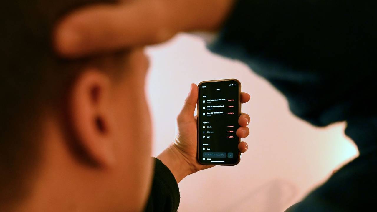 Mann schaut sich Trading-App eines Neobrokers mit Aktienkursen an