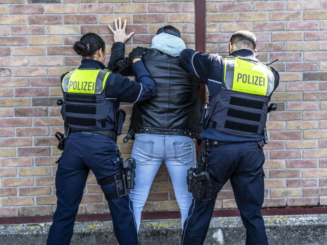 Ein Mann in Handschellen wird von Polizistinnen und Polizisten abgeführt.