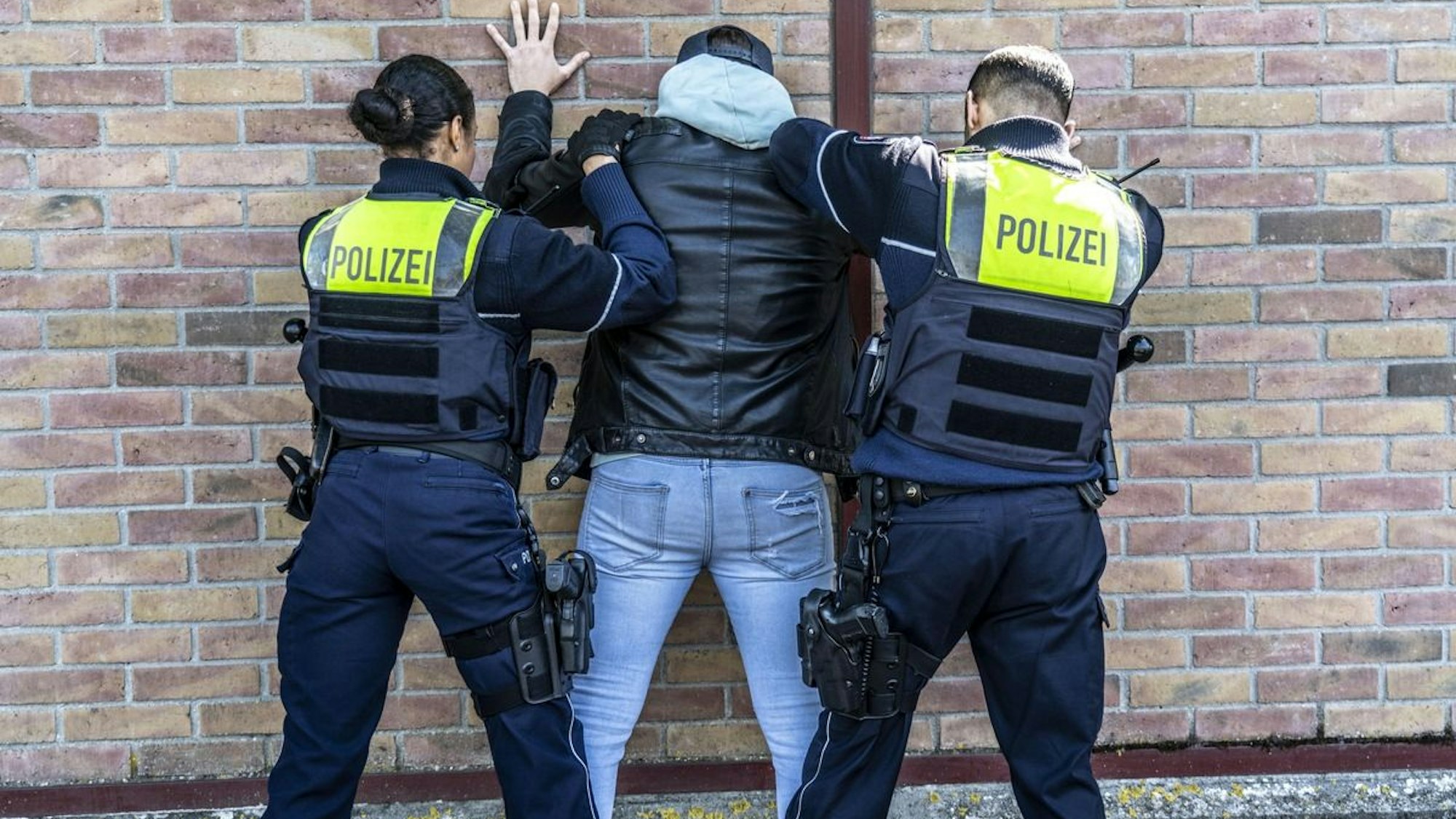 Ein Mann in Handschellen wird von Polizistinnen und Polizisten abgeführt.