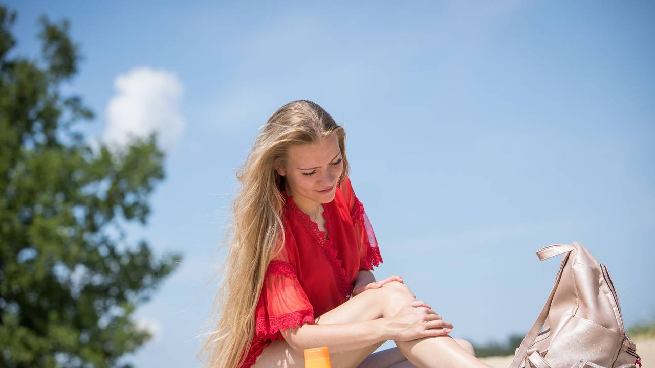 Eine junge Frau verteilt Sonnencreme auf ihrer Haut