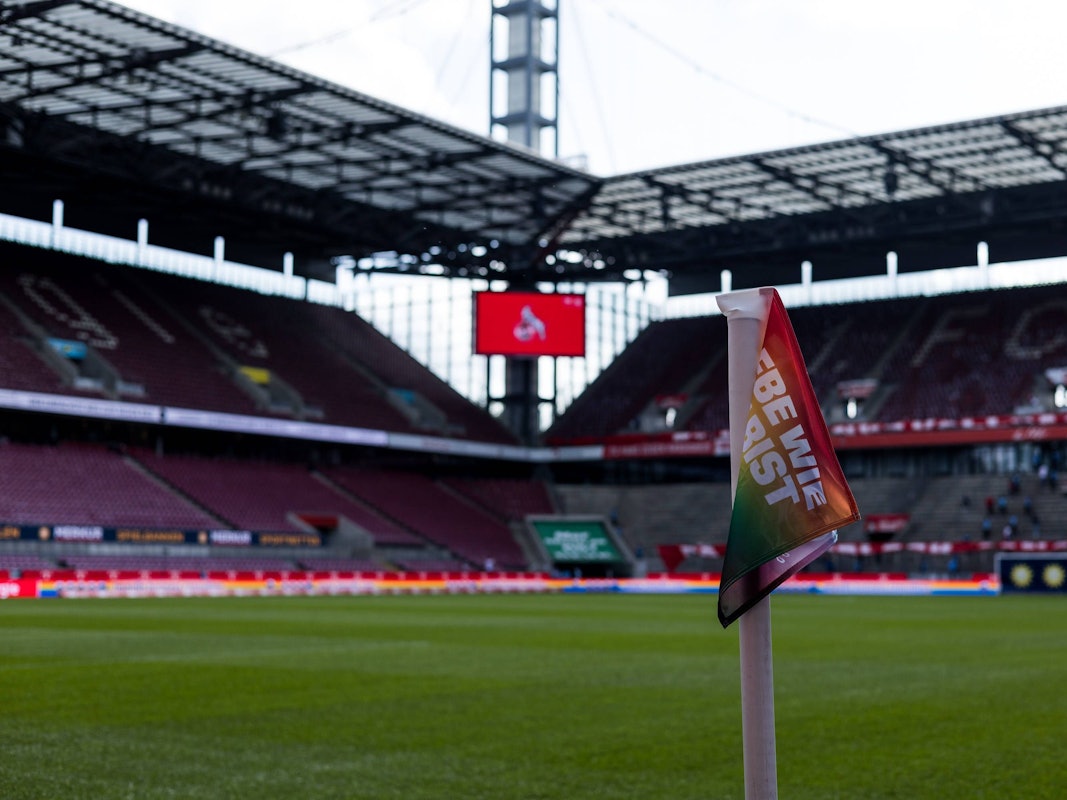 Blick ins leere Rhein-Energie-Stadion mit Regenbogen-Eckfahne.
