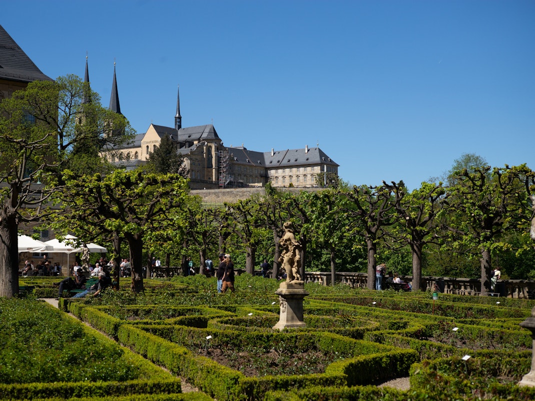 Blick auf ein Klostern, darunter ein Biergarten in einem Park
