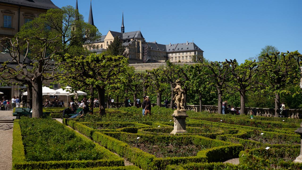 Blick auf ein Klostern, darunter ein Biergarten in einem Park